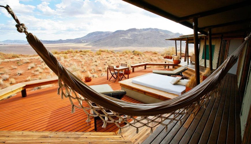 un'amaca sulla veranda di una suite del wolwedans dunes lodge con deck in legno, letto e sedie a sdraio