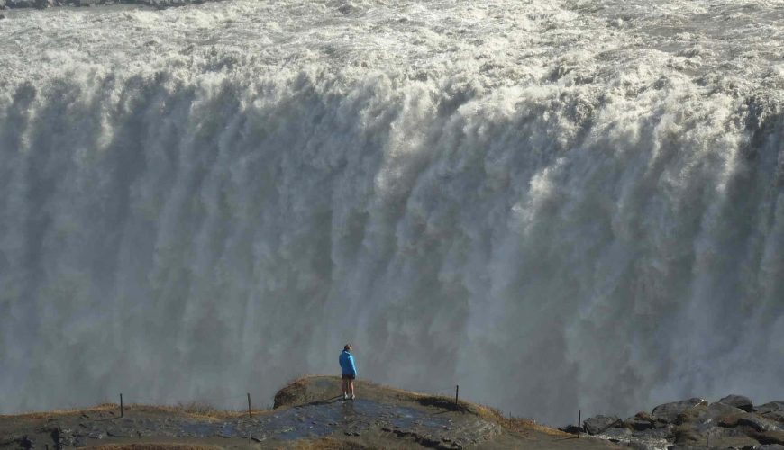 uomo di fronte alla cascata di Dettifoss