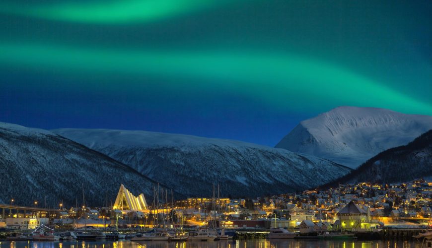aurora boreale dietro Tromsø con la cattedrale artica illuminata in evidenza